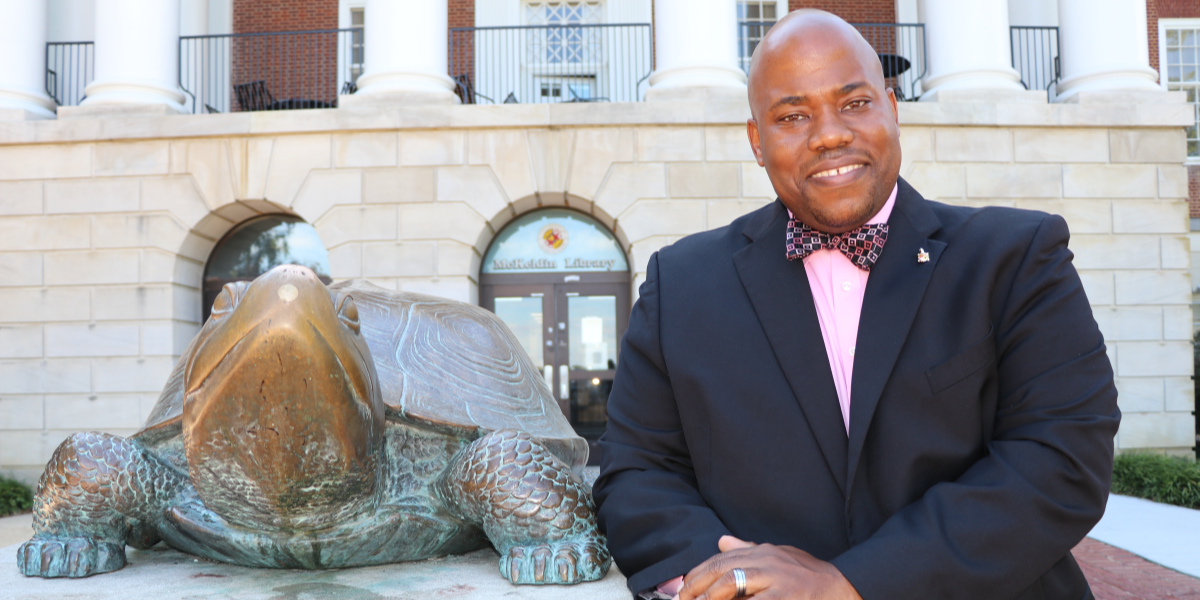 Image of Aaron Wilson standing next to Testudo