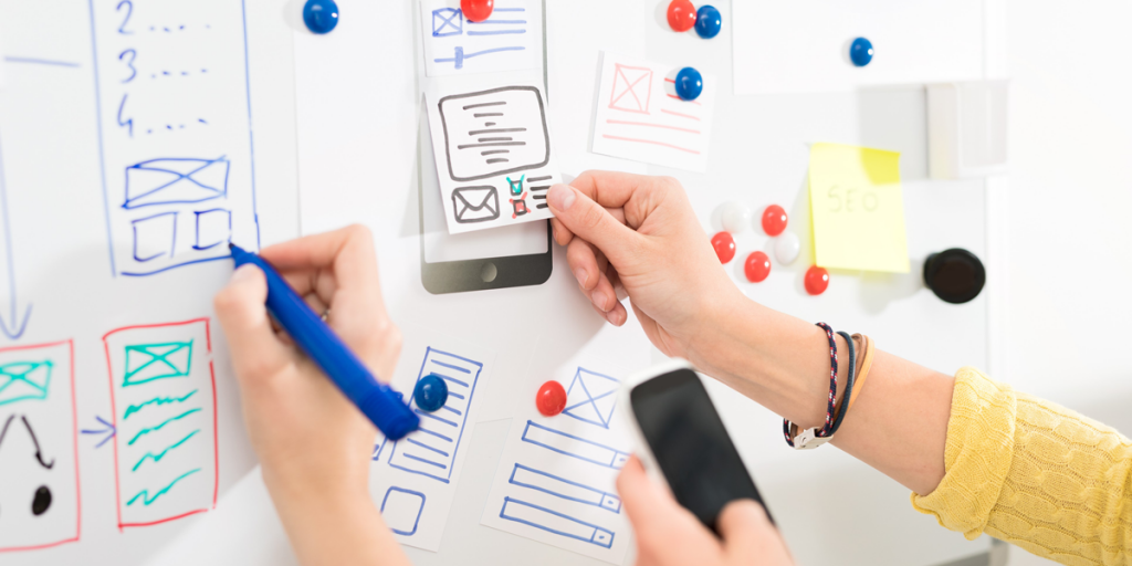 hands reaching out with prototypes on a whiteboard