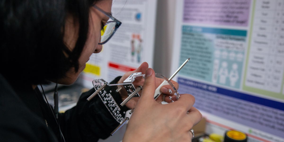 A photo of a person building and looking closely at a small robot.