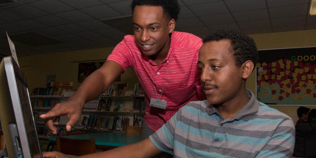 photo of two men looking at a computer and one is pointing to something on screen