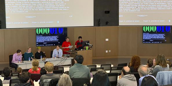 row of people sitting in front of an auditorium with large projectors