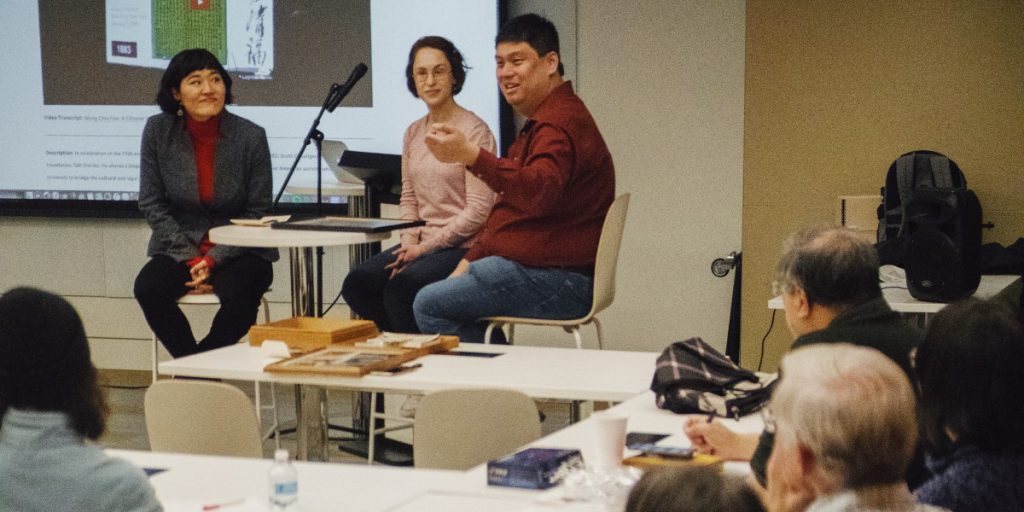 three people sitting at the front of the room in front of a projector screen